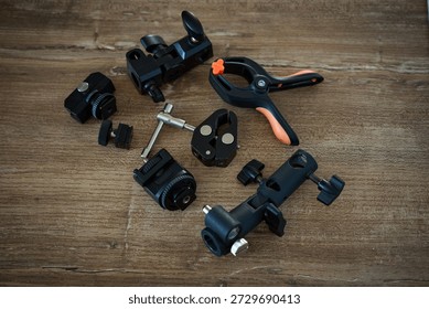 Various camera accessories and tools are arranged on a wooden table with a dark finish in a workshop setting