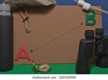 Various Camping Equipment Surrounding A Corkboard Showing A String Connecting Points A And B