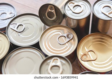 Various Canned Food In Metal Cans On Wooden Background , Top View / Canned Goods Non Perishable Food Storage Goods In Kitchen Home Or For Donations