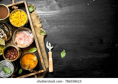 Various canned fruits, vegetables, fish and meat in tin cans on old tray. On the black chalkboard. - Powered by Shutterstock