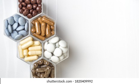 Various capsules and pills with dietary supplements or medicines in hexagonal jars are in the form of a honeycomb - Shutterstock ID 1820409992