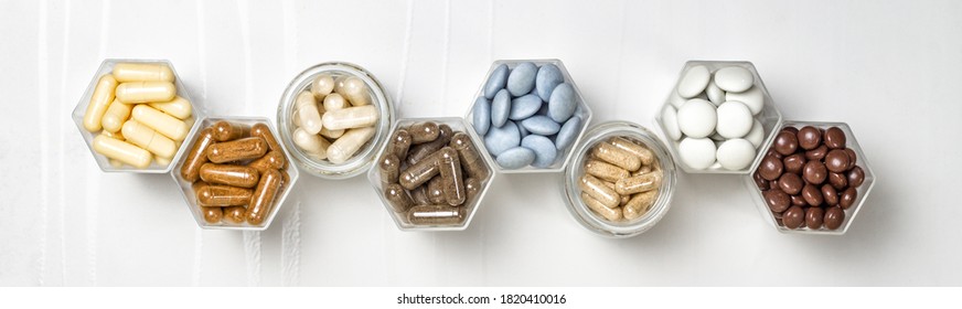 Various capsules and pills with dietary supplements or medicines in hexagonal jars are in the form of a honeycomb - Shutterstock ID 1820410016