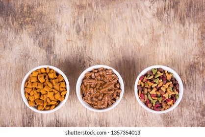 Various Cat Food. Different Types Of Cat Food. Bowls With Cat Food On Wooden Background