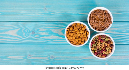 Various Cat Food. Dry And Wet Cat Food. Copy Space. Bowls With Cat Food On Wooden Background.