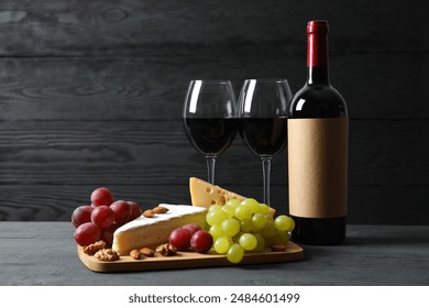 Various cheeses, grapes, nuts and red wine on a wooden table - Powered by Shutterstock