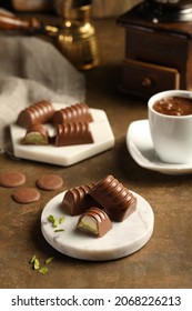 Various chocolate pralines with pistachio on on brown background.