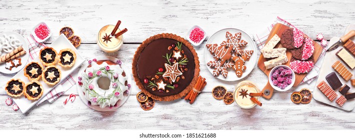 Various Christmas Holiday Desserts And Sweets. Overhead View Table Scene On A White Wood Banner Background. Bundt Cake, Chocolate Pie, Mincemeat Tarts, Cookies, Fudge And Eggnog.