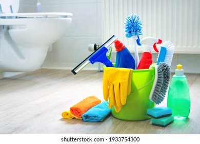 Various cleaning items and supplies in a bucket on the bathroom floor