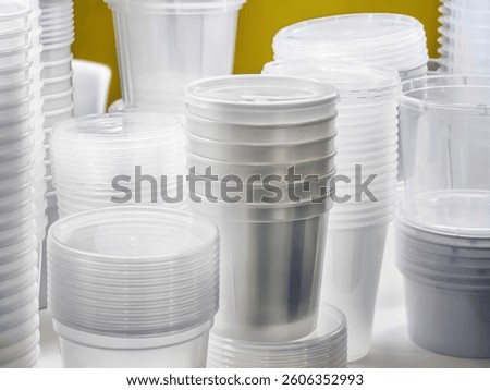 Various clear plastic cups and containers are stacked in neat rows on a table, showcasing their versatility for hosting events or casual gatherings in a well-lit area.