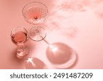 various cocktail glasses on sunny pink background, top view