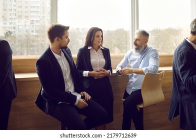 Various colleagues communicate and discuss information after business event or corporate training. Three employees in business attire talk to each other during informal meeting during office break. - Shutterstock ID 2179712639