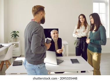 Various Colleagues Having Casual Conversation At Workplace In Office During Work Break. Men And Women Of All Ages Work Together In Cozy, Comfortable And Friendly Atmosphere. Concept Of Friendly Team.