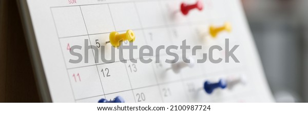 Various color thumb tack pins on calendar as\
reminder. Important business days\
concept