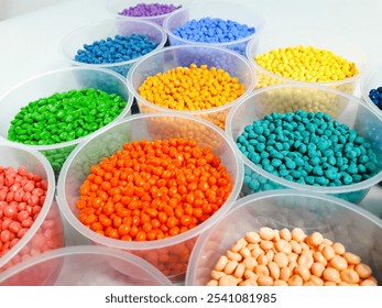 Various colored masterbatch granules in a cup on a white background.Polymer carriers of color pigments in the plastics industry
