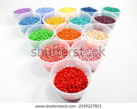 Various colored masterbatch granules in a cup on a white background.Polymer carriers of color pigments in the plastics industry