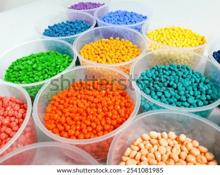 Various colored masterbatch granules in a cup on a white background.Polymer carriers of color pigments in the plastics industry