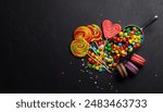 Various colorful candies, lollipops, and macaroons. Flat lay over stone background with copy space