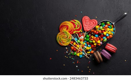 Various colorful candies, lollipops, and macaroons. Flat lay over stone background with copy space - Powered by Shutterstock