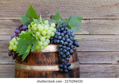 Various Colorful Grapes On Wine Barrel On Outdoor Sunny Garden In Front Of Wooden Wall