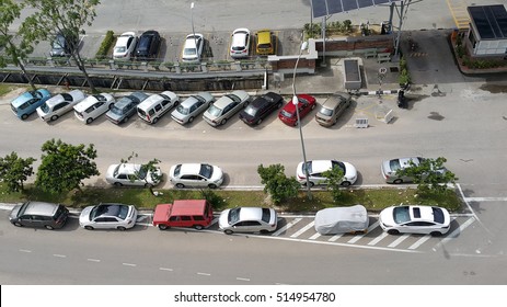 Various Colors, Make And Shapes Of Cars Grouped In Alignment  Parked In Various Position In Rows On Road As Viewed From Above