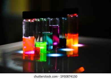 Various colourful analytical sample in glass vial in an inorganic chemistry laboratory experiment on the UV light by a woman scientist