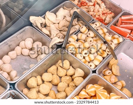 Various complementary foods for sukiyaki and shabu dishes such as meatballs, crab sticks, odeng or fish cake, sausages inside cooler display case. Concept for ultra processed junk food, diet, healthy.