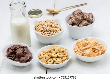 Various conrflake cereals in bowls and milk.