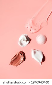 Various cosmetic smears on a pink background, top view. Lather soap foam, aloe vera clear transparent spot, facial moisturizer, body milk lotion and lipstick texture