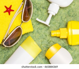 Various cosmetic sunscreen products for face and body skin care, towel and sunglasses. Lotion, milk, spray and cream. Cosmetics containing sun protection factor