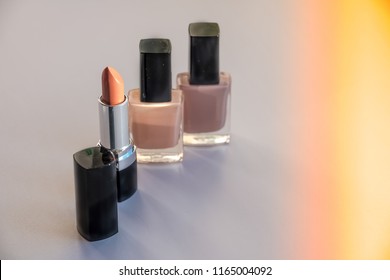 Various Cosmetics isolated on white background. Sun rays. Copy space.Decorative cosmetics.Fashion colors concept.Nude makeup.Selective focus.Nail polish,nail varnish bottles and beige lipstick.