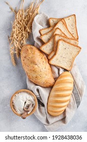Various crispy breads and buns, wheat flour and ears on light gray concrete background table. Top view flat lay with copy space