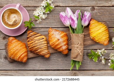 Various croissants and coffee on wooden board and tulip bouquet. French breakfast. Top view flat lay - Powered by Shutterstock