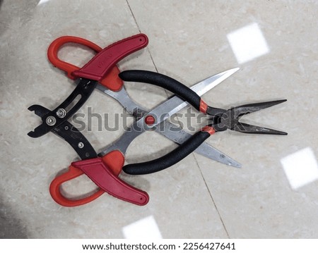 various cutting tools like scissor, cutting plier and wire stripper used in the electronics lab placed on a white floor
