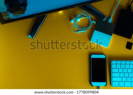 Various different objects with yellow retro background, phone, screen, white keyboard. Top view.