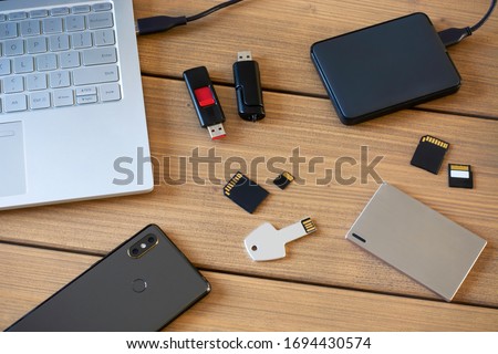 Various digital data storage devices. Usb sticks, external hard drive, SD cards, mini and micro SD cards, laptop and smartphone. Flat lay. 