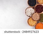 Various dried  beans, lentils, mung, chickpea, pea  assortment in wooden bowls. Legumes on white table top view. Vegan protein sources food, copy space