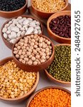 Various dried  beans, lentils, mung, chickpea, pea  assortment in wooden bowls. Legumes on white table top view. Vegan protein sources food, copy space