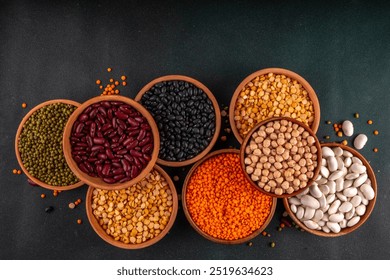 Various dried beans, lentils, mung, chickpea, pea assortment in wooden bowls. Legumes on white table top view. Vegan protein sources food, copy space