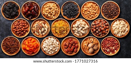 Various dried fruits and nuts bowls on a stone table. Top view flat lay