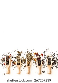 Various Of Dried Tea In Wooden Scoops On White  Table