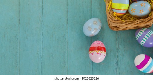 Various Easter eggs arranged in wicker basket on wooden surface