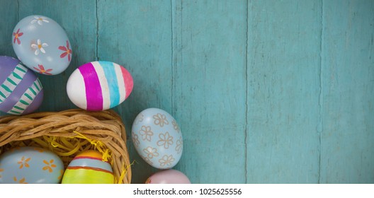 Various Easter eggs arranged in wicker basket on wooden surface