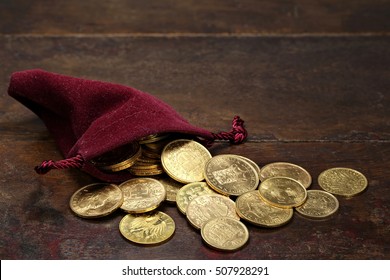 various European circulation gold coins from the 19th/20th century in a velvet purse on rustic wooden background