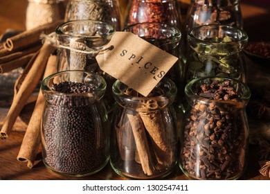 Various exotic spices in glass jars with SPICES text on paper tag.