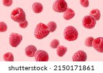 Various falling fresh ripe raspberries on light pink background, horizontal composition