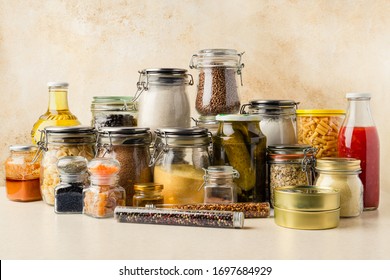 Various food supplies including grains, condiments, tomato sauce, oil in glass bottles and jars, dry pasta, canned produce on kitchen table. Sustainability concept. Horizontal orientation - Shutterstock ID 1697684929