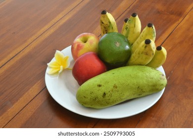 Various fruits, mango, apple, banana, mango, on a wooden table with white plates - Powered by Shutterstock