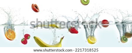 Various fruits splashing in water. Side panoramic view on white background.