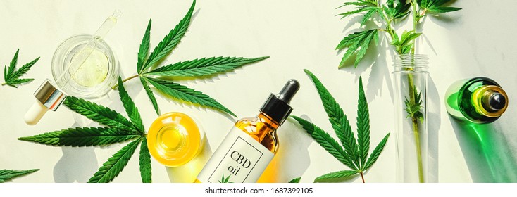 Various glass bottles with CBD oil, THC tincture and hemp leaves on a marble background. Flat lay, minimalism. Cosmetics CBD oil.