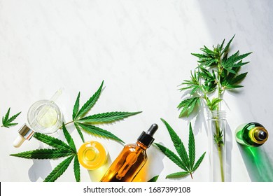 Various glass bottles with CBD oil, THC tincture and hemp leaves on a marble background. Flat lay, minimalism. Cosmetics CBD oil.